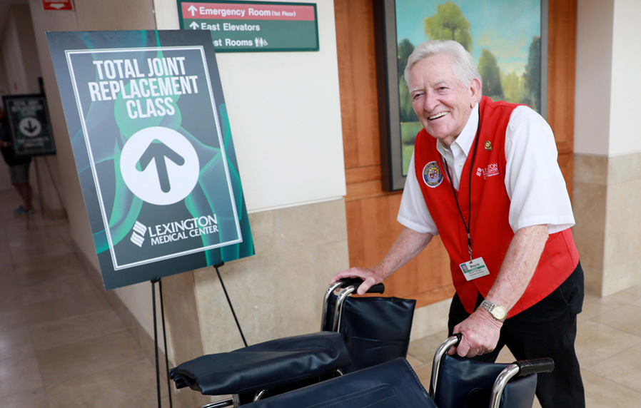 A volunteer smiling and delivering a wheelchair.